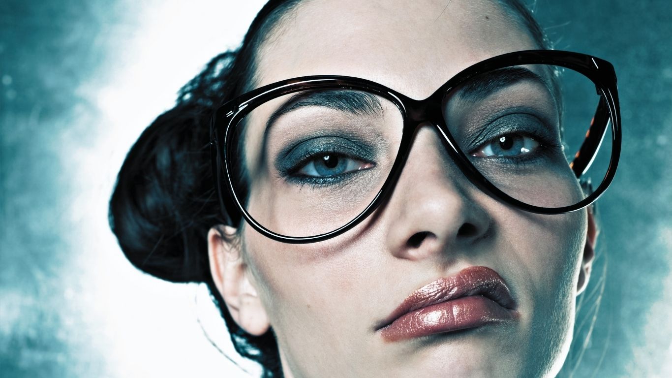 Woman wearing glasses with her hair in a bun, looking annoyed.
