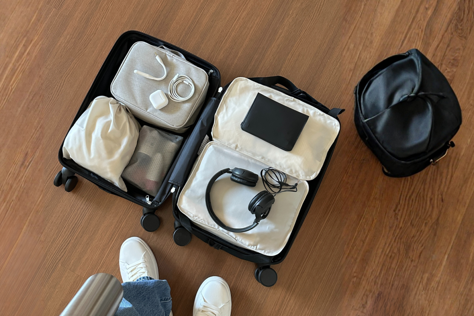 Open suitcase on a wooden floor with items in compartment bags, neat and clean.